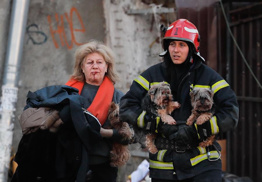Rescatista ayuda a mujer herida y sus perros a resguardarse tras bombardeo en Kiev. Foto: EFE/EPA/SERGEY DOLZHENKO