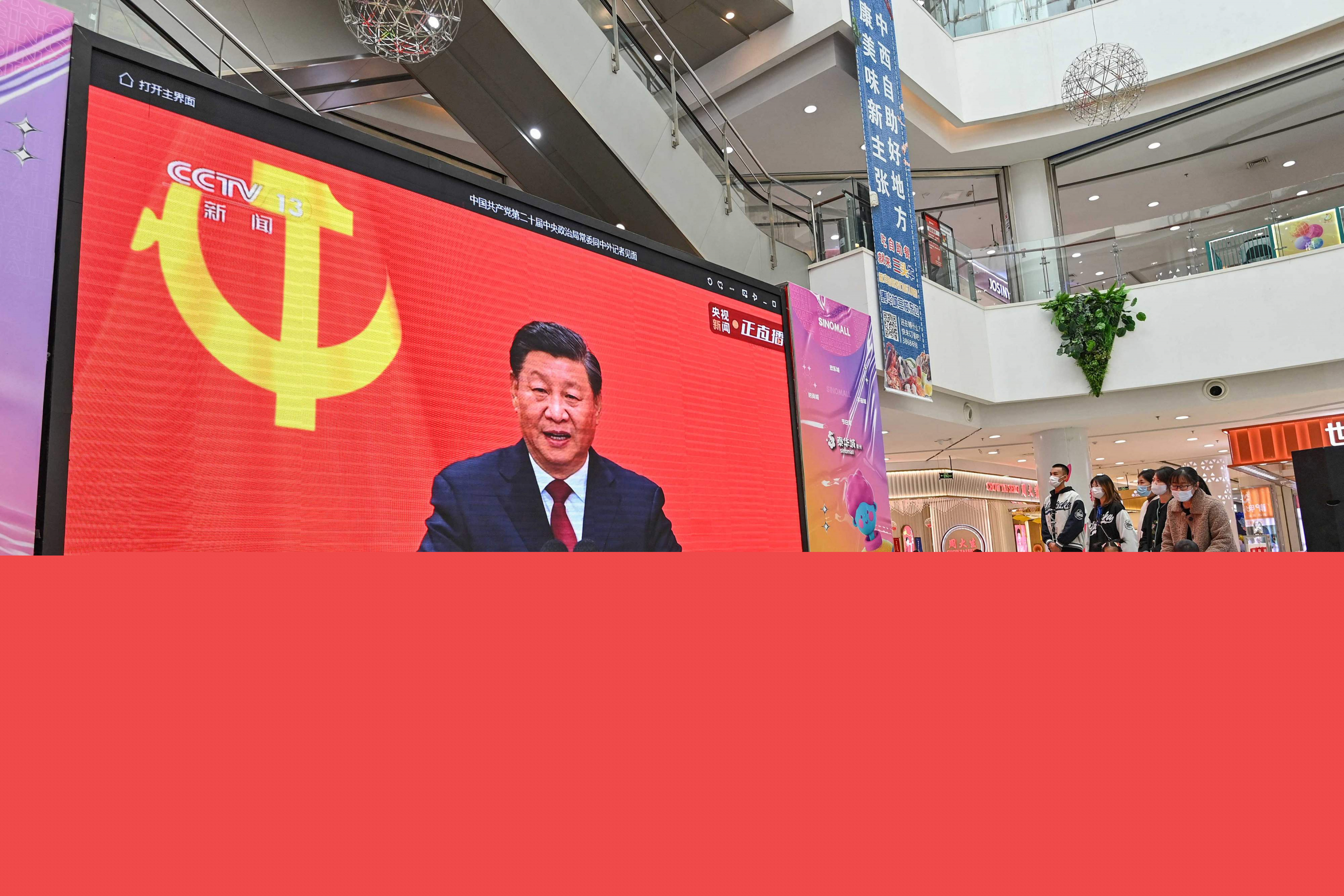 La gente ve una transmisión en vivo del presidente de China, Xi Jinping, hablando durante la presentación del Comité Permanente del Politburó del Partido Comunista de China, en una pantalla en un centro comercial. Foto: AFP.